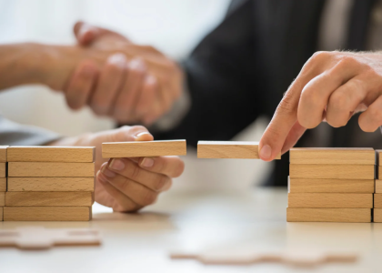 zwei Personen bauen eine Brücke aus Holzbausteinen